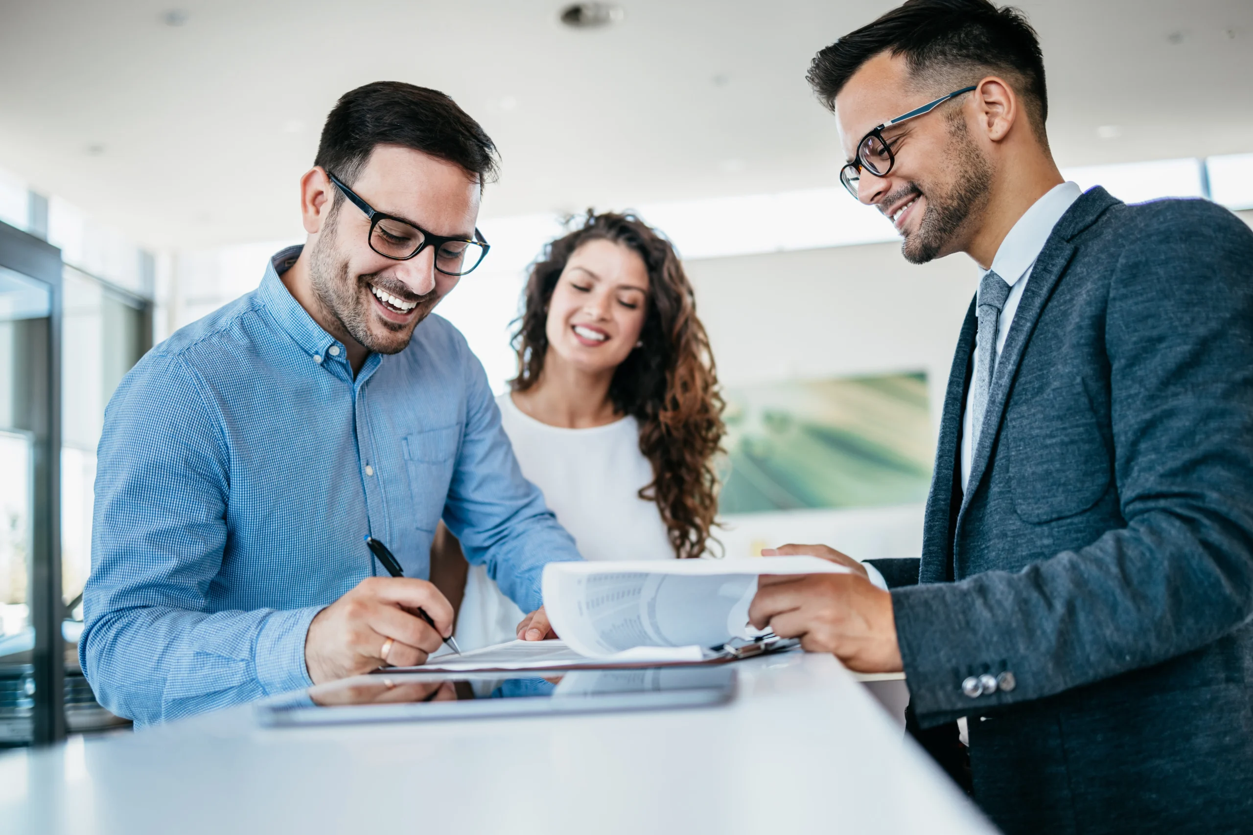 Middle age couple choosing and buying car at car showroom. Car salesman helps them to make right decision. Man signs buyers contract.