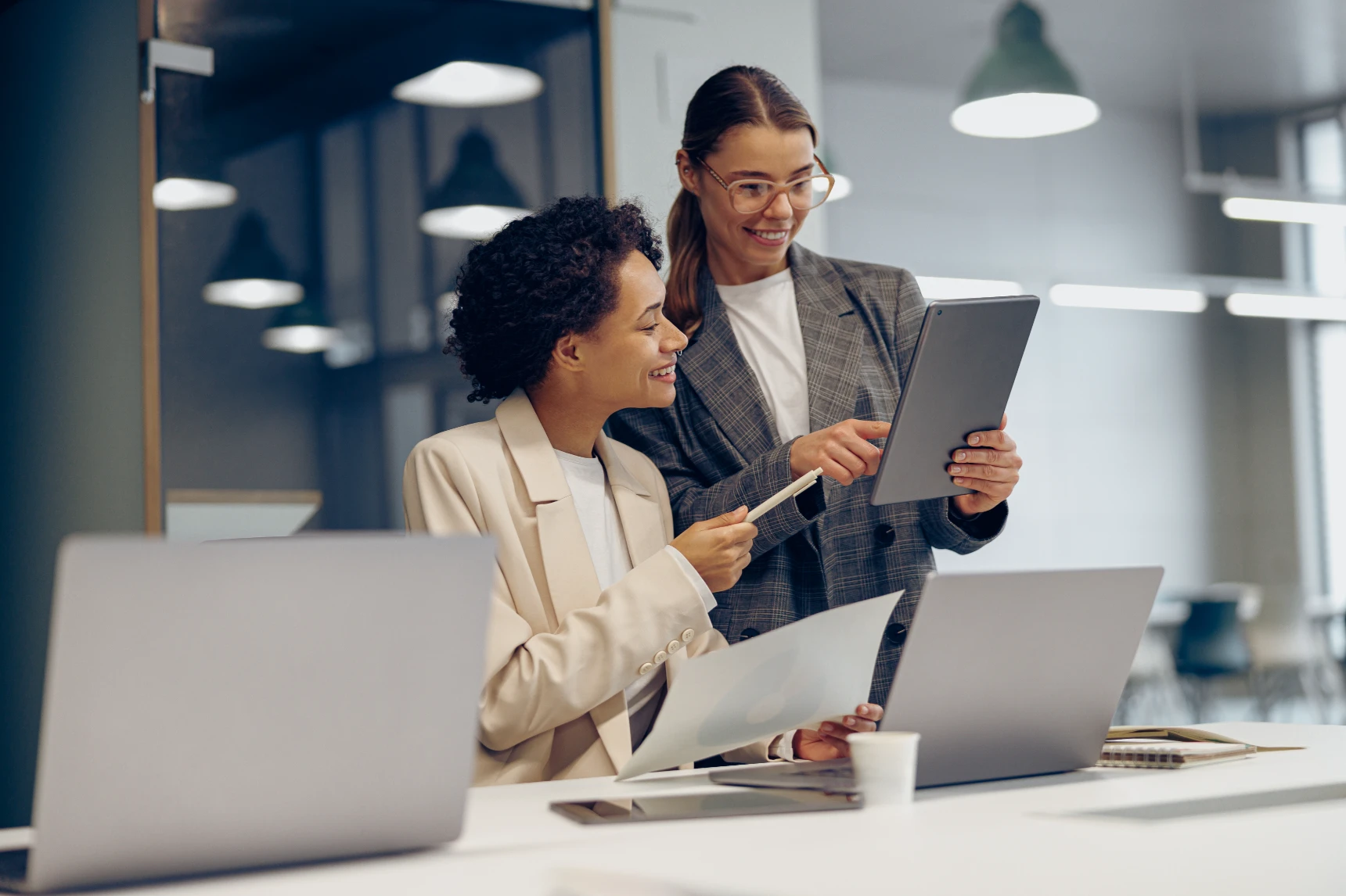 Stylish female executives managers discussing financial accounting papers and using digital tablet